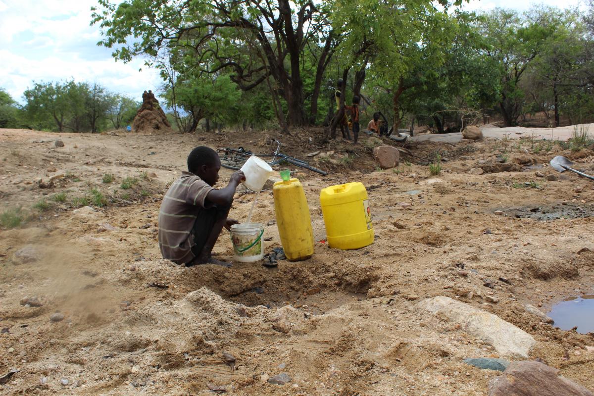  A boy collects water from a dug-out well in Lokales, Amudat.